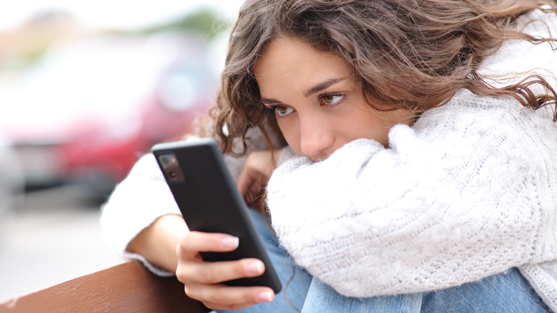 Eine Frau schaut erschöpft auf ihren Smartphonebildschirm.
